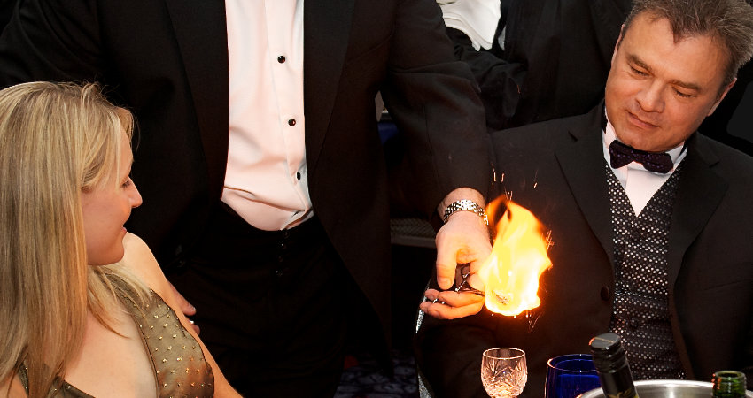 Kevin Bird performing close-up fire magic at a black-tie dinner